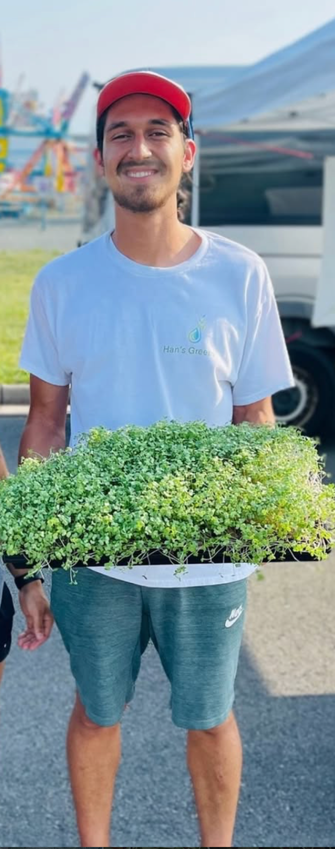 Han, founder and grower at Han’s Greens, holding trays of microgreens